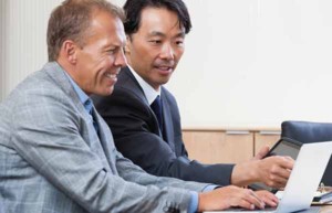 Two male colleagues wearing business suits working together on a computer
